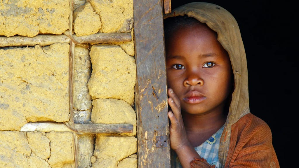 Niña de Kenia al costado de una puerta
